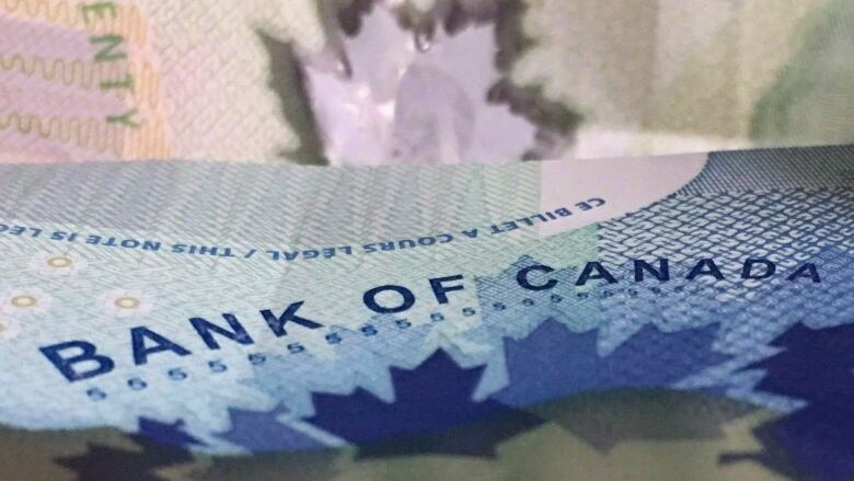 A five-dollar Canadian bill is shown in close-up.