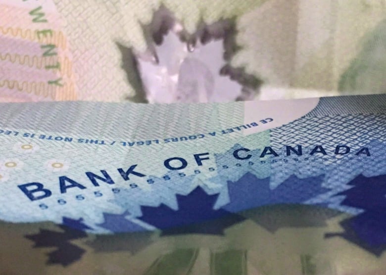 A five-dollar Canadian bill is shown in close-up.