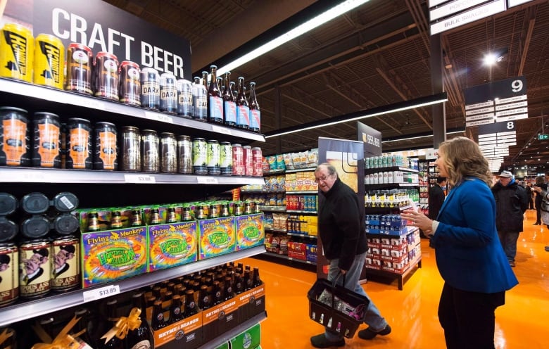 Shoppers pass beer on grocery store shelves. 