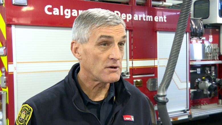 Steve Dongworth, chief of the Calgary Fire Department, is seen in uniform talking in front of a red fire truck.