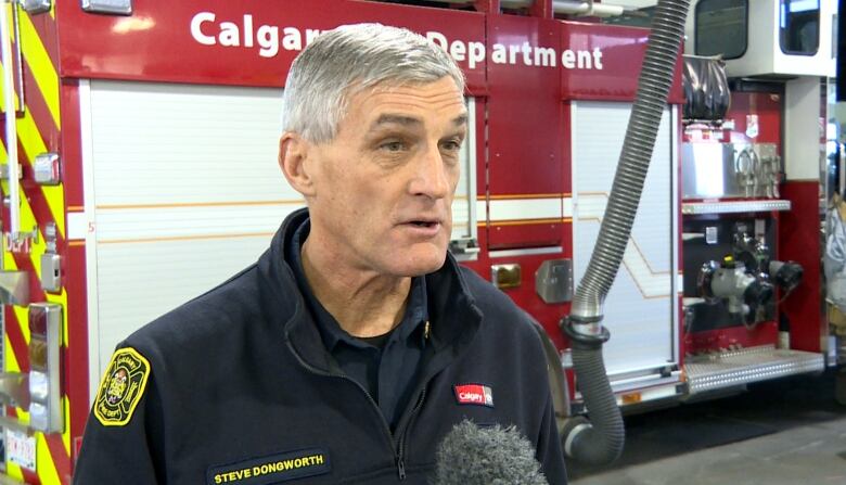 Steve Dongworth, chief of the Calgary Fire Department, is seen in uniform talking in front of a red fire truck.