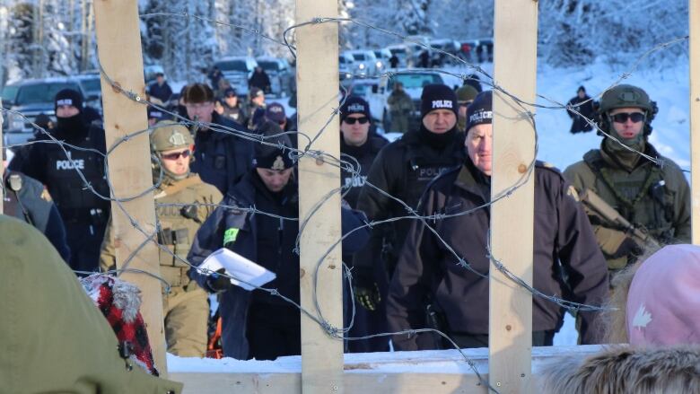 Police and activists face off through a barbed-wire barricaded.