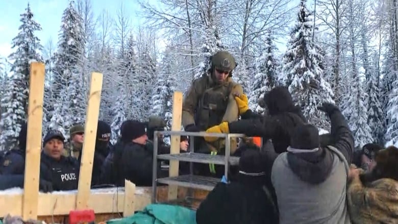 police officers climb a barricade