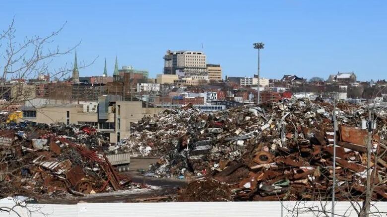 Piles of rusty metal in foreground, buildings in background