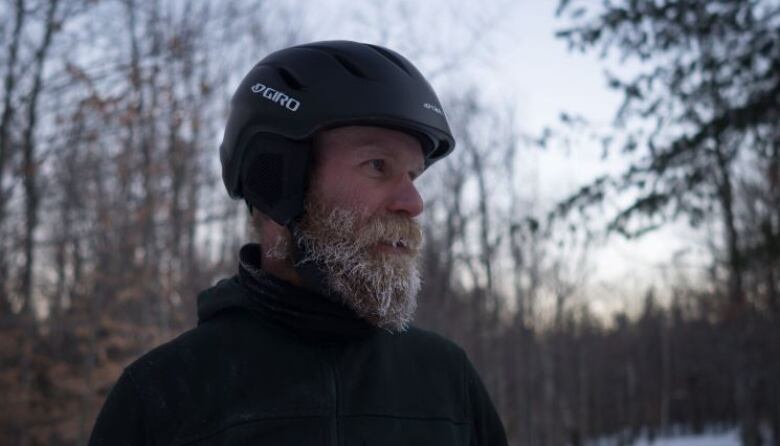 a man with a beard, wearing a black helmet, looking right. 