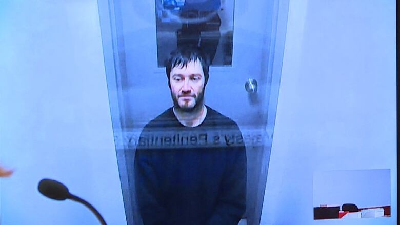 A man appears via video screen for legal proceedings.