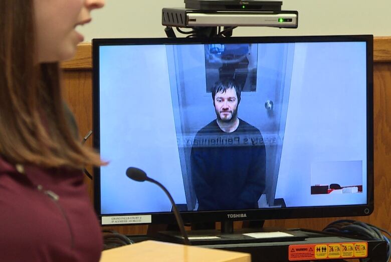 A man appears via video screen for legal proceedings.