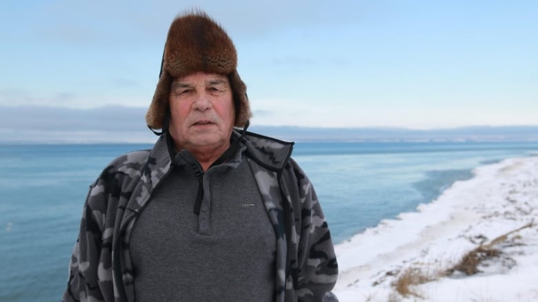 A man stands near the ocean