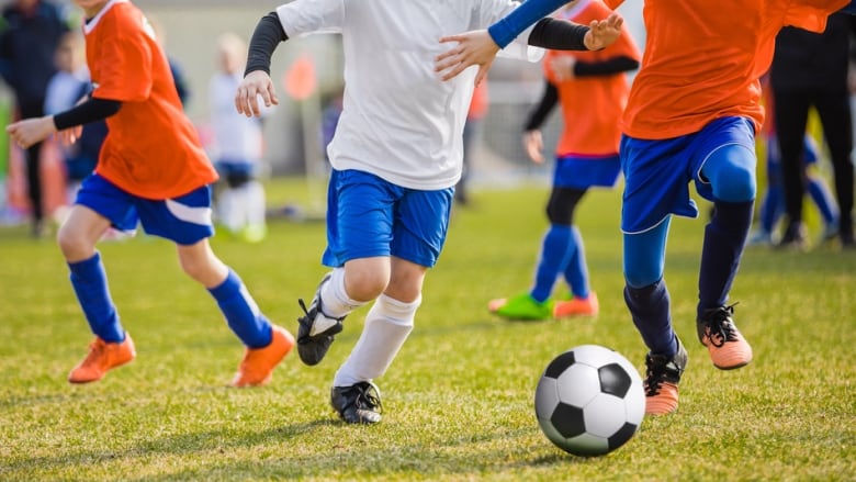 Children play soccer on a field.