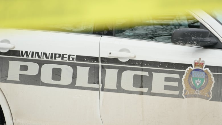 A white Winnipeg police cruiser is seen behind yellow tape.