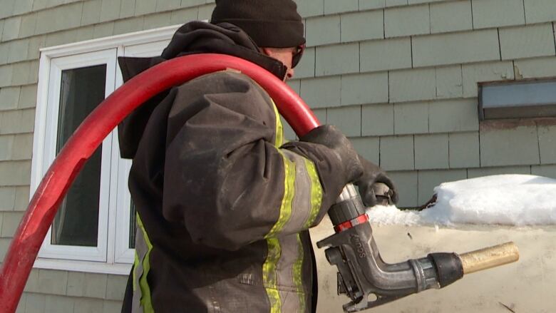 A worker fills a home heating oil tank on a snowy day 