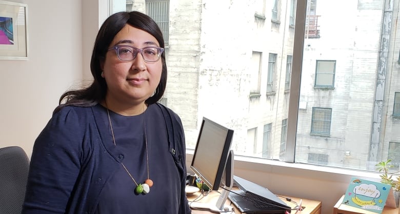 A woman in a purple shirt and glasses. 