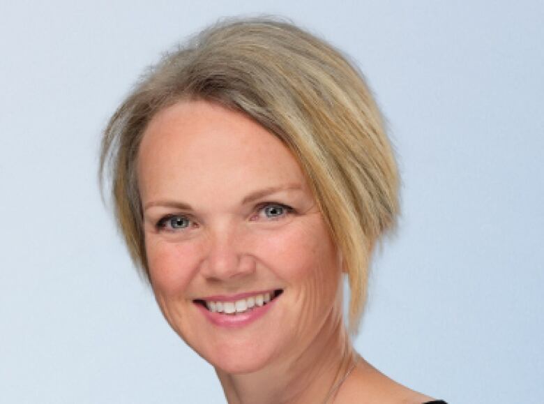 Smiling woman in black shirt with short blonde hair. 