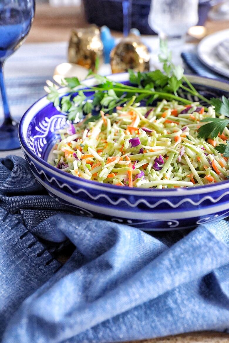 Closeup on a blue bowl of broccoli walnut slaw on a table with blue and white decor.