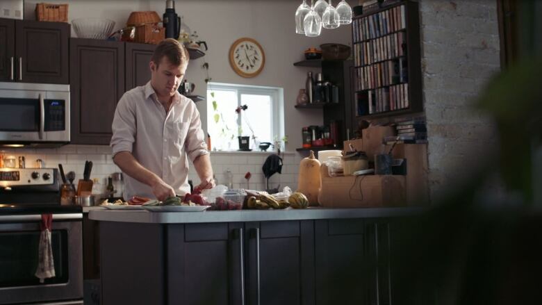 A man at a counter chops vegetables in a kitchen.