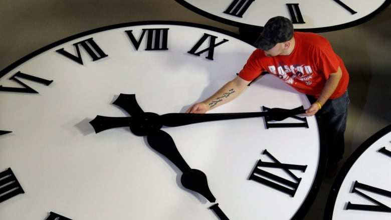 A man moves the hands of a gigantic clock.