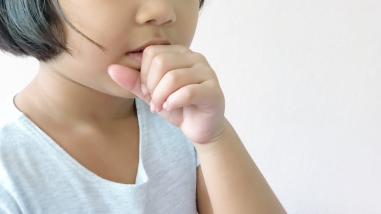 A child coughs while covering their mouth with their hand