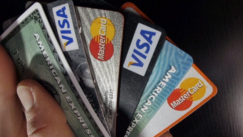 Several credit cards are fanned out in a person's hand.