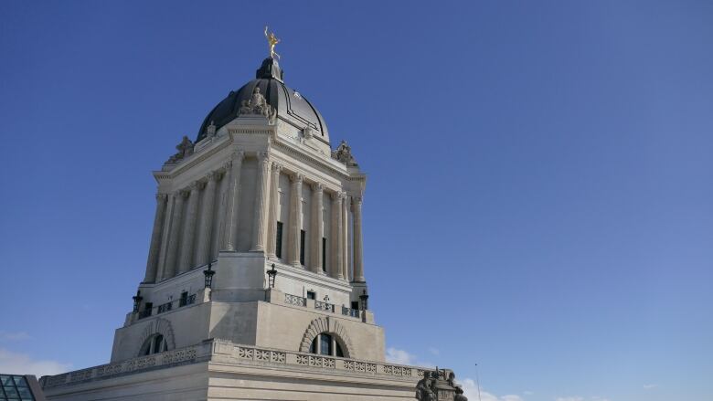 The dome of a building is seen with a golden statue on top