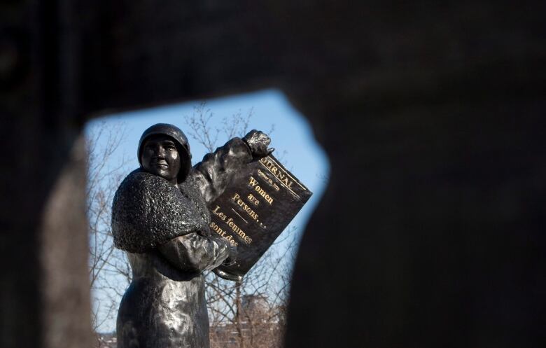 Statue of a woman holding up a document that reads 