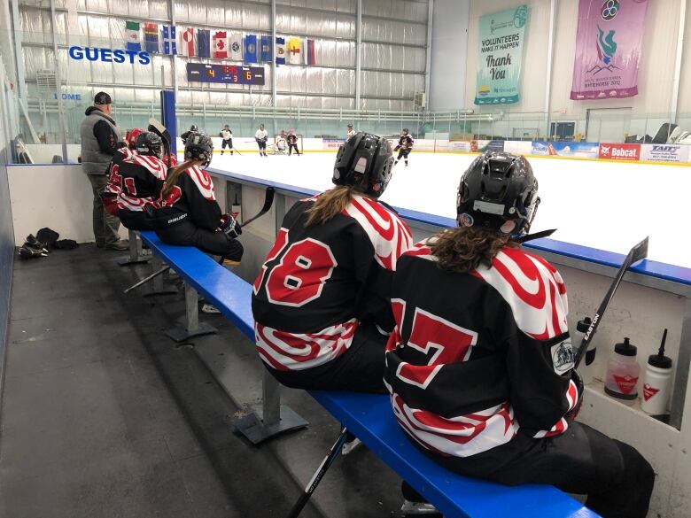 Some hockey players are seen on the bench during a game. 