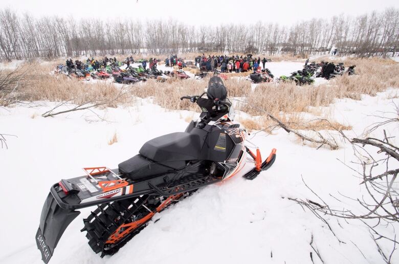 A black snowmobile sits on a snowy field.