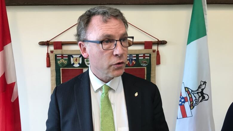 A man in a green tie speaks into a microphone.