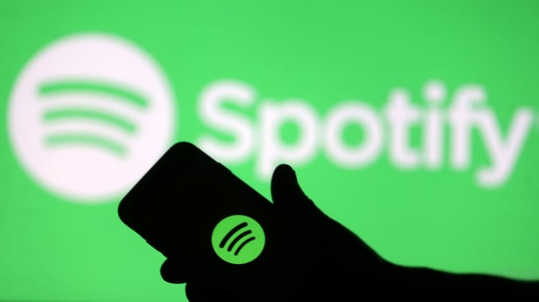 A smartphone is seen in front of a screen projection of Spotify logo, in this picture illustration taken April 1, 2018. REUTERS/Dado Ruvic/Illustration - RC1BCDB28F90