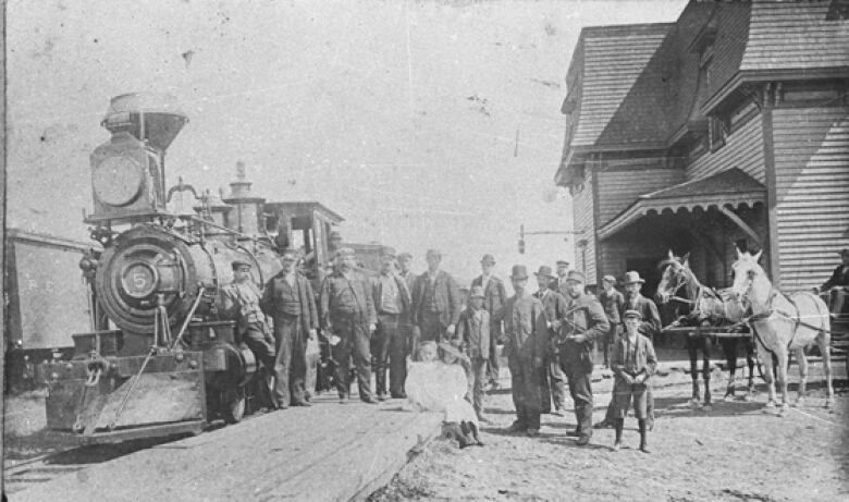 Old black and white photo of train arriving at station.