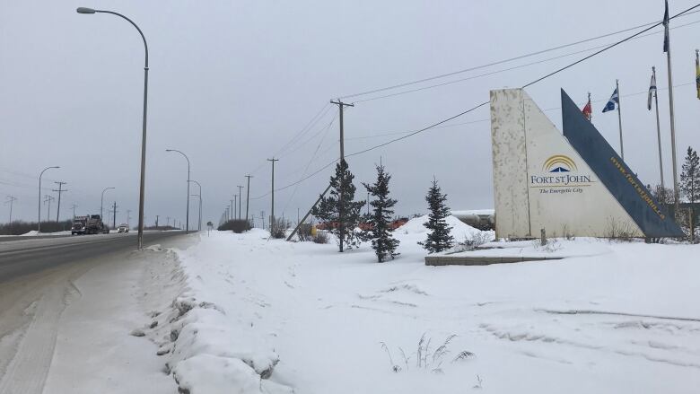 A dirty snow highway is seen with a white cement sign that reads 