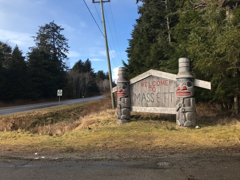 A sign with two small totem poles next to it reads 'Welcome to Massett'.