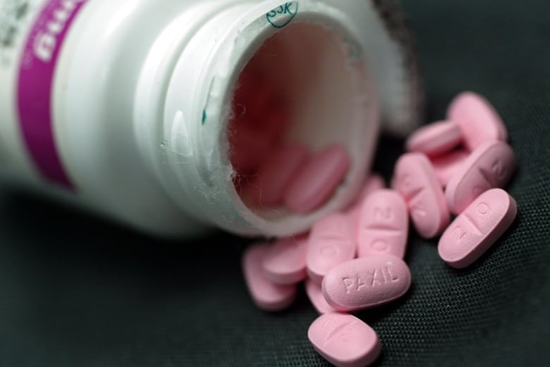 Pink anti-depressant pills spill out of a bottle.