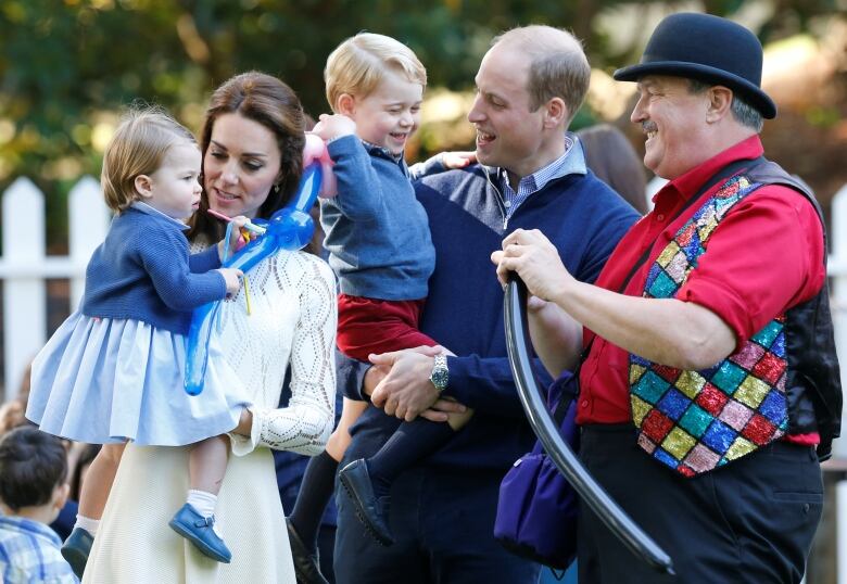 Adults hold children at a garden party.