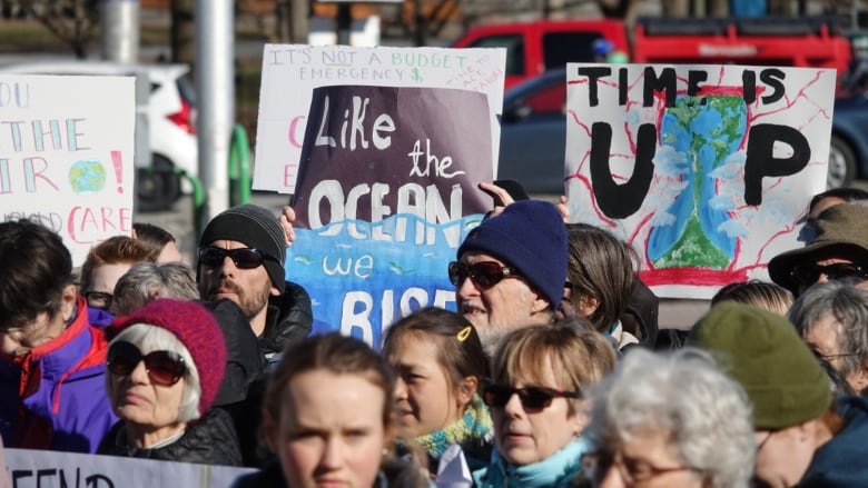 A group of people hold up homemade signs warning about climate change