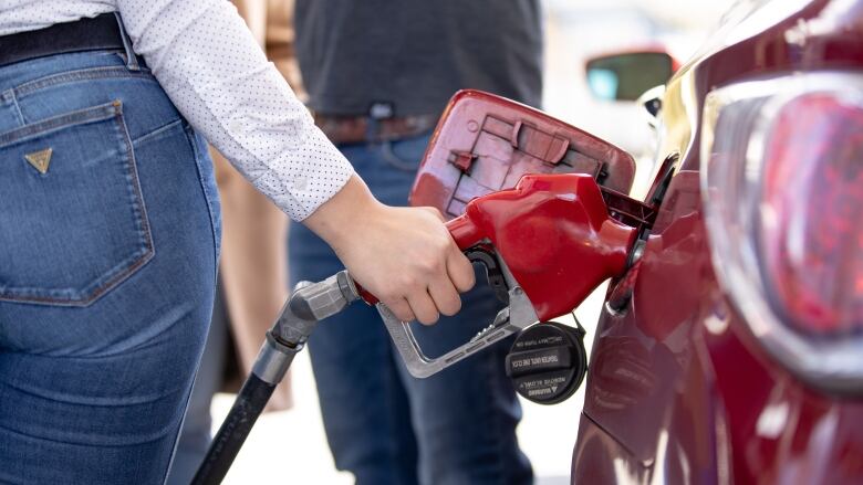 A woman fills up her tank at a gas station.