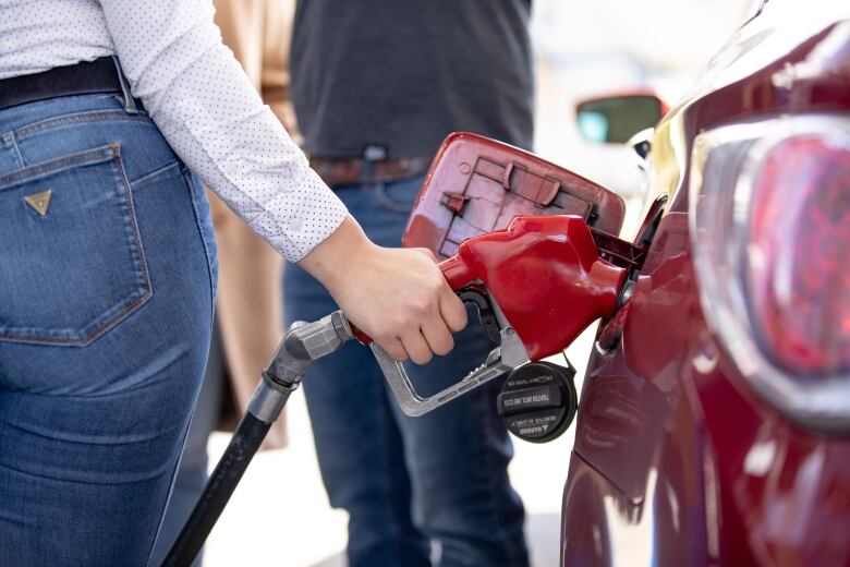 A woman fills up her tank at a gas station.