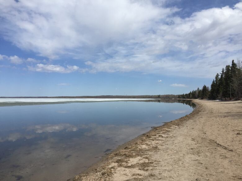 Water to the left and a sandy beach to the right under a blue sky. 