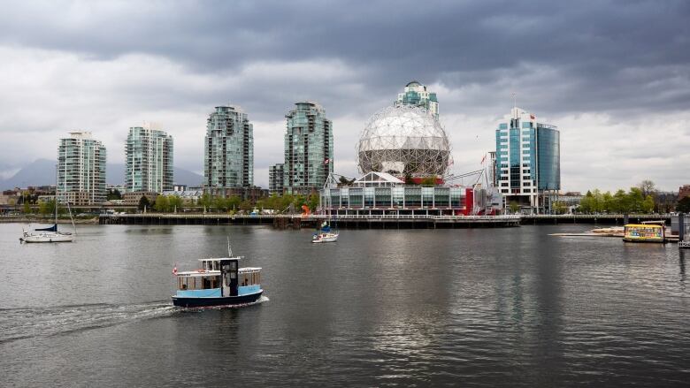 a False Creek Ferry chugs by Science World in Vancouver's False Creek