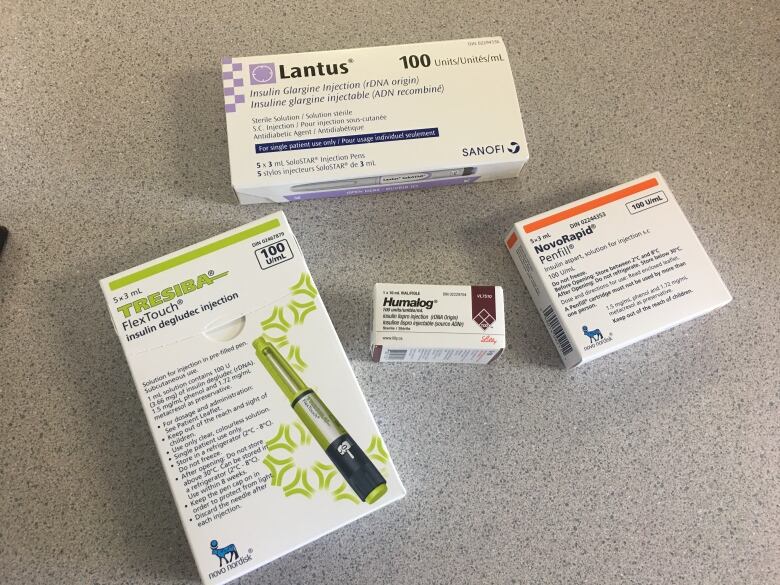 The boxes of four different brands of insulin medications are shown on a table.