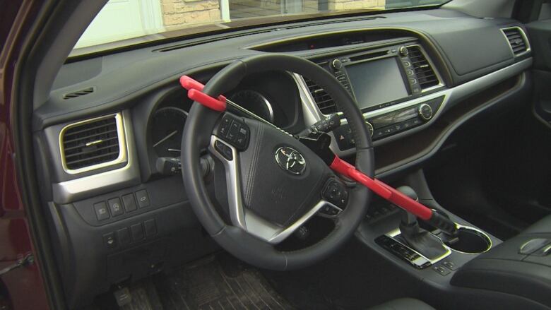 The black interior of a vehicle with a red locking device across the wheel. 