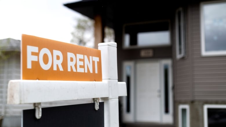 A orange sign that reads for rent. 