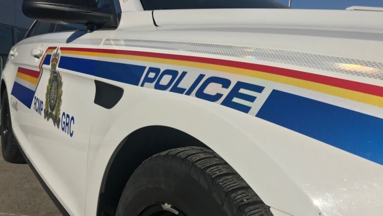 A white police cruiser with blue yellow and red stripes that says RCMP