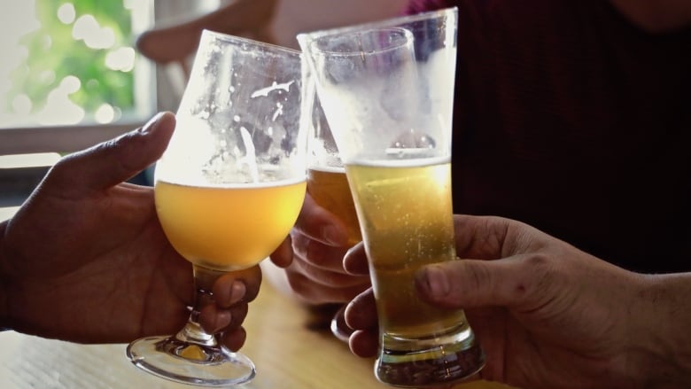 Glasses of beer are held and clinked together