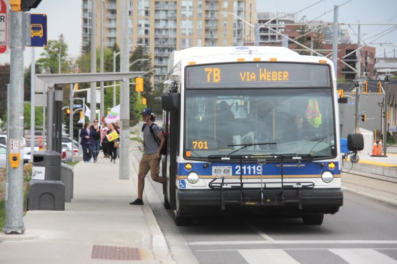 A man waring a cap gets off a bus.