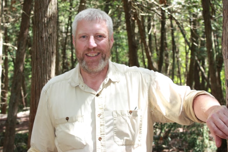 A man stands in the forest smiling