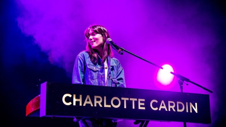 A woman standing at a keyboard bearing the words 'Charlotte Cardin' smiles. 