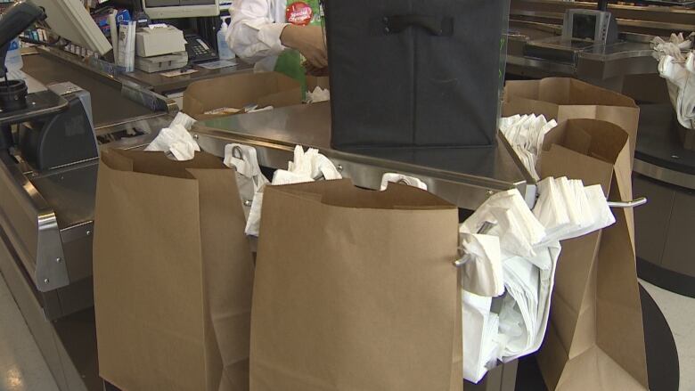 A grocery store checkout with both plastic and paper bags 