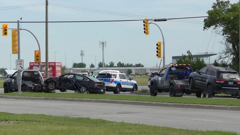 Three damaged vehicles are towed away from a police scene.