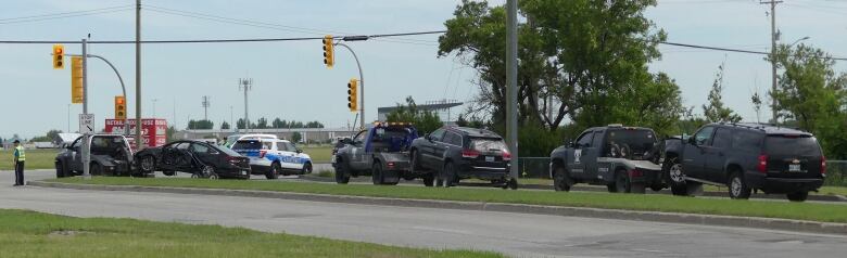 Three damaged vehicles are towed away from a police scene.