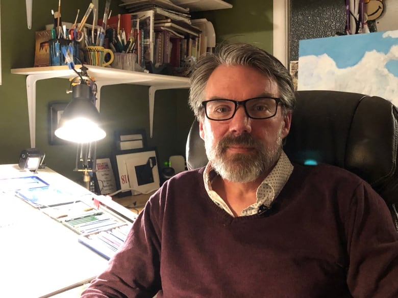 A man sits in front of his drafting board.